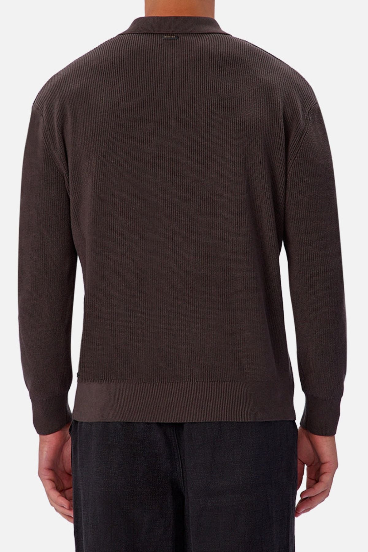 A person is seen from the back wearing an Industrie The New England Polo Knit, a dark brown ribbed long-sleeve 100% cotton sweater, with black pants against a plain light gray background.