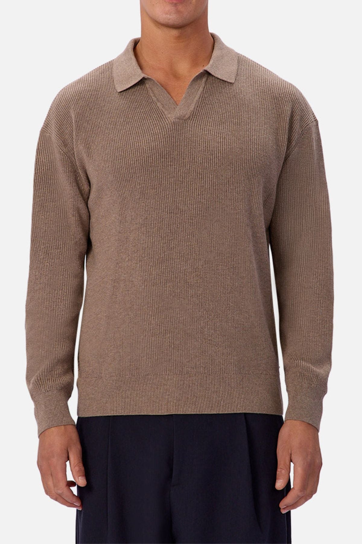 A person wears the Industrie The New England Polo Knit in light brownโ100% cotton, long sleeves, and collaredโpaired with black pants, standing against a plain white background.