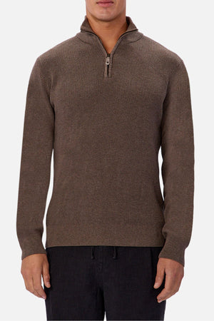 A person is wearing the Industrie The New England Zip Neck Knit, a brown men's cotton quarter zip sweater with ribbed knit texture, and black pants, standing against a plain white background.