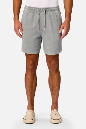 A person wearing Industrie The New Mallorca Short menβs cotton shorts in light gray, a white shirt, and beige slip-on shoes stands against a plain white background.