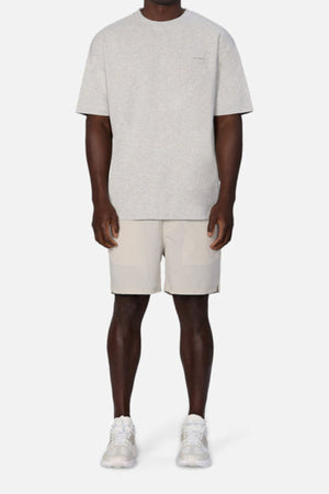 A person dressed in Industrie The Newport Tee, an oversized fit light gray T-shirt, paired with beige shorts and white sneakers stands against a plain white background. This 100% cotton outfit looks casual and comfortable.