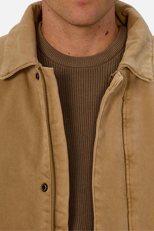 A close-up of a person wearing the Industrie The Oklahoma Jacket over a brown ribbed sweater. The shot highlights the casual-fit jacket’s clean lines, showing only the lower face and upper chest.