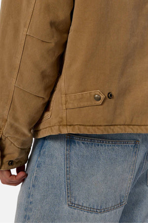 Wearing the Industrie The Oklahoma Jacket with button details and light blue jeans, only the jacket’s lower half and the jeans’ upper section are seen, focusing on the back pocket and side seam.