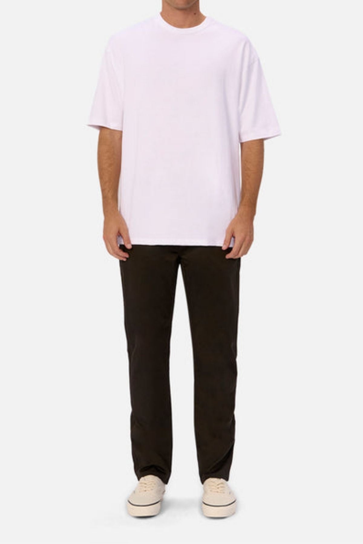 A person faces forward, wearing a plain white oversized T-shirt, Industrie The Regular Cuba Chino Pant with a wider leg fit, and light sneakers against a plain white background. The person's face is not visible.