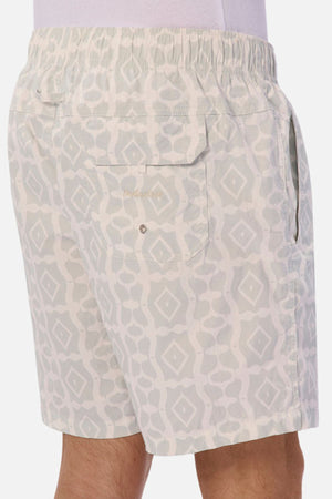 A man shows off the Industrie Saratoga Swim Short, highlighted by its distinct geometric print in light gray. These quick-drying shorts feature a practical back pocket with a button and an elastic waistband for added comfort.