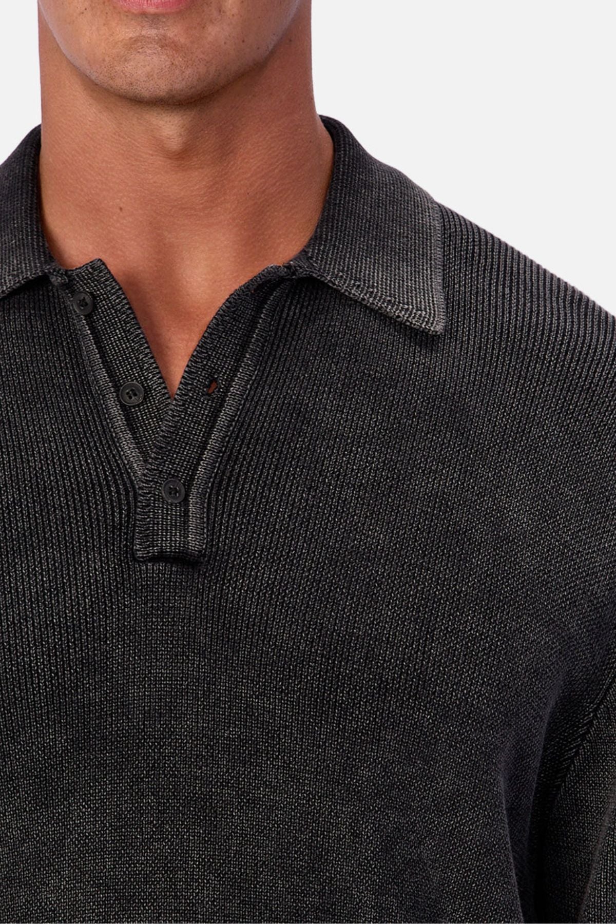 A close-up of a person wearing the Industrie The Sawtelle Knit—a textured, dark gray, long-sleeve sweater with a collar and partial button placket, made from 100% cotton. Only shoulders to mid-chest are shown; the face is partially visible.