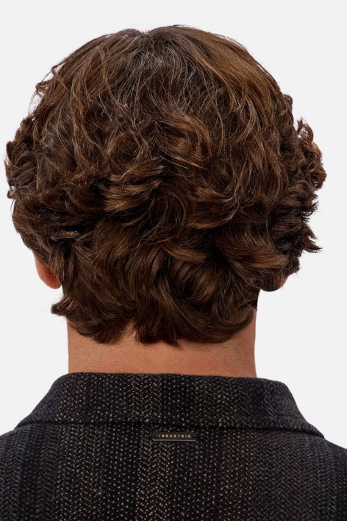 The image shows the back view of a person with thick, wavy brown hair wearing the Industrie The Sonoran Long Sleeve Shirt in a dark textured fabric, highlighting the shirt’s stylish look and their hairstyle against a light gray background.