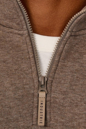 Close-up of the Industrie The Staunton Tracktop with branded brown zipper, featuring "INDUSTRIE" on the pull, worn over a white shirt. The image shows the neckline and part of the wearer’s neck.