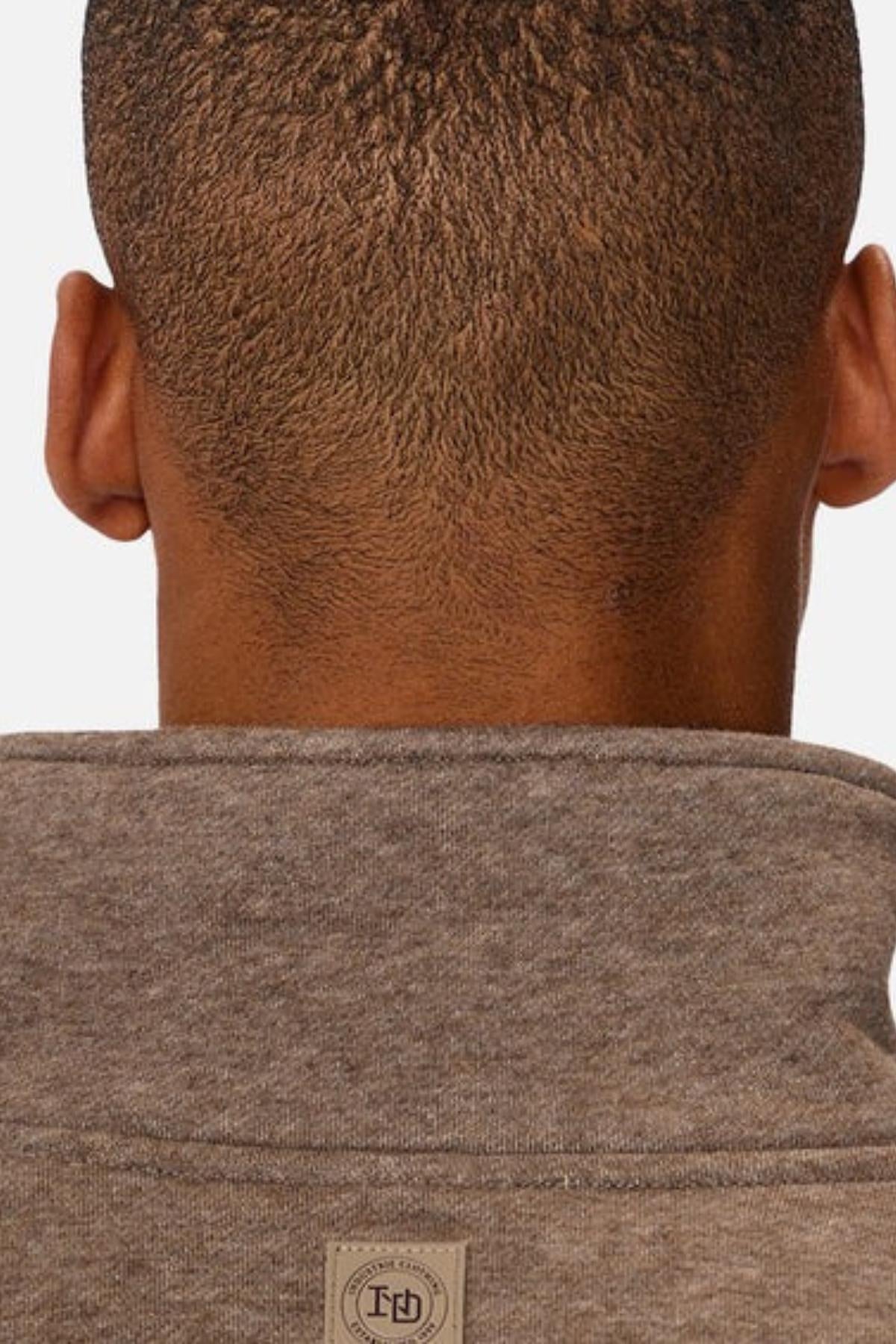 A close-up shows the back of a person's head with short, textured hair, wearing the Industrie The Staunton Tracktop in heather gray, featuring branded trims and a small rectangular tag near the collar.
