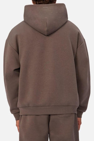 A person is shown from the back wearing an Industrie The Tech Del Sur Hood sweatshirt and matching brown sweatpants. The hood is up, covering the head, and both pieces are made of advanced athletic fabric. The background is plain white.