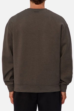 A person is seen from behind in a loose-fitting, dark gray Industrie The Tech Del Sur Sweat with long sleeves, breathable fabric, and a subtle back neck logo, paired with black pants against a plain light-colored background.