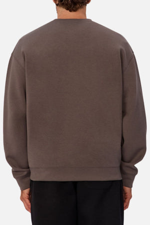 A person is seen from behind wearing the Industrie The Tech Del Sur Sweat, a loose-fit, long-sleeve top paired with black pants, showcasing modern athleisure style against a simple light background.
