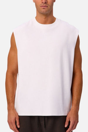 A man wearing the Industrie The Tech Port Sleeveless Tee and dark pants stands facing forward against a plain background.