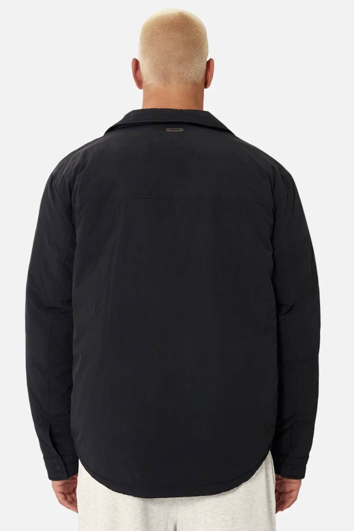 A person with short, bleached blond hair is seen from behind wearing the Industrie The Twin Cullman Jacket in black and light-colored pants, standing against a plain light gray background, embodying the signature Industrie style.