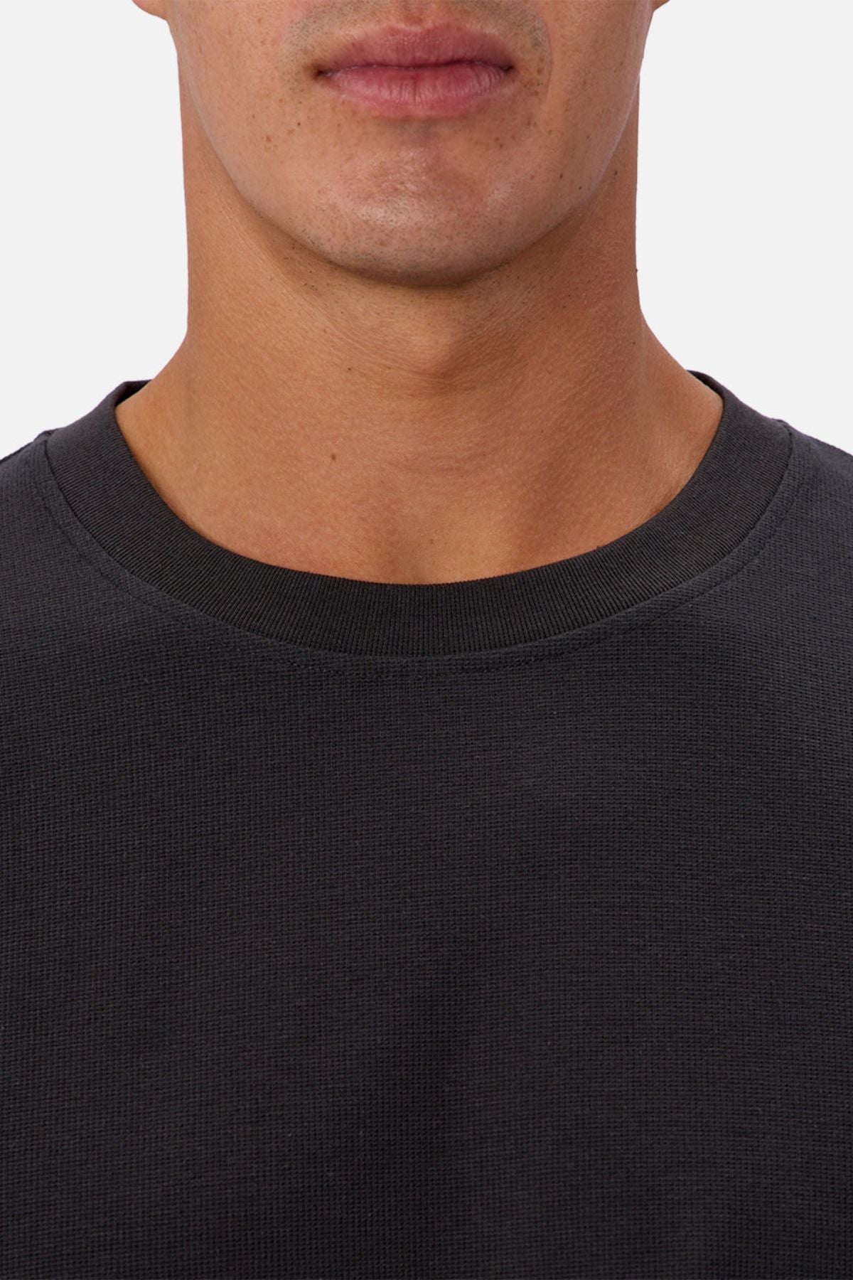 A close-up shows the lower face and neck of a person wearing the Industrie The Waffle Long Sleeve Tee against a light, plain background. Their lips are closed and only part of their face is visible.