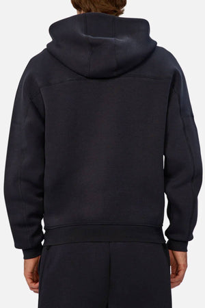 A person is seen from behind wearing the Industrie The Washington Zip Thru jacket and matching black pants. The loose-fit jacket, ideal for everyday wear, has the hood up but not covering their head.