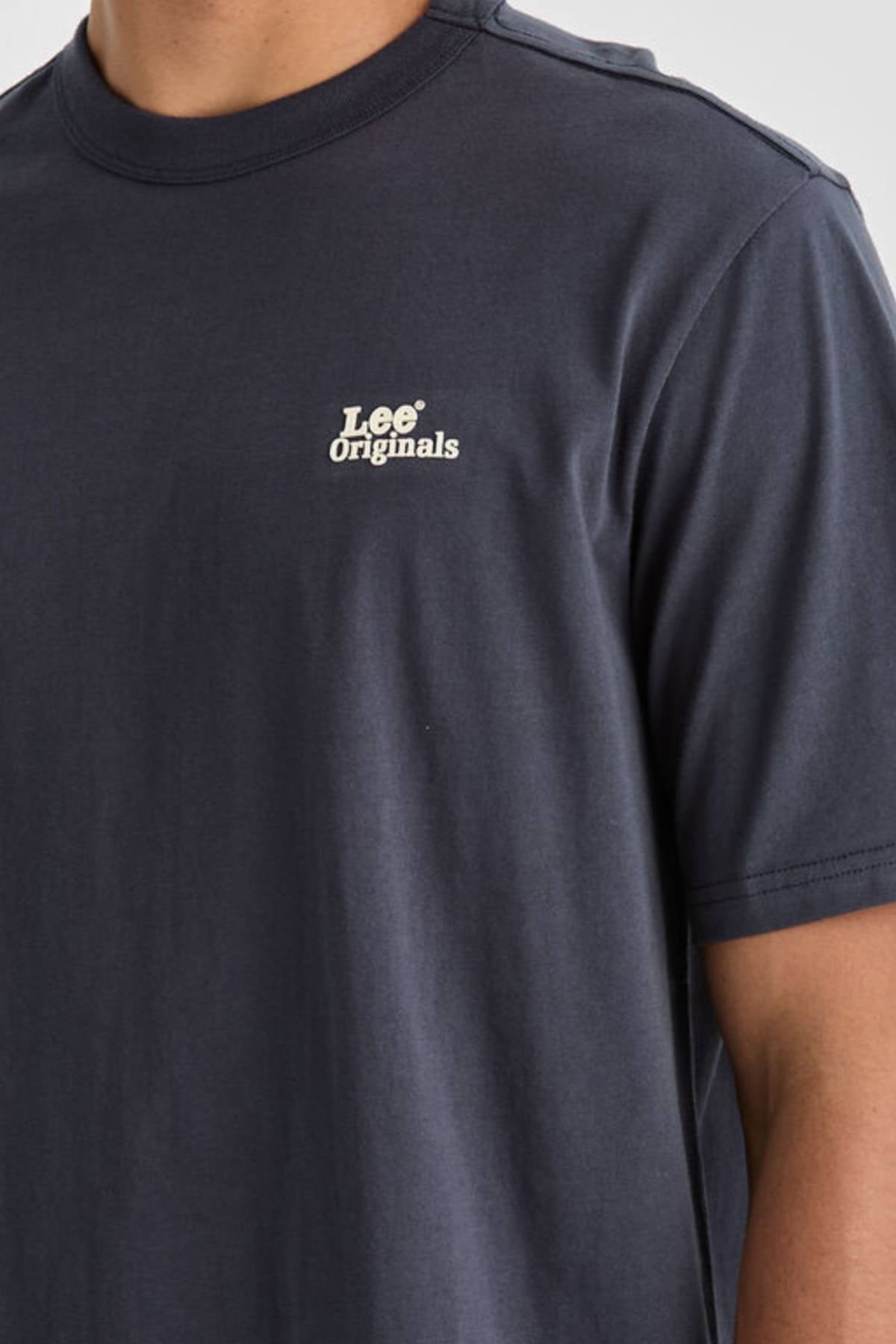 Someone wearing the Lee Originals Relaxed Tee in dark blue, featuring a white "Lee Originals" logo on the left chest. Only the upper torso and part of one arm are shown. Made from 100% cotton for all-day comfort.