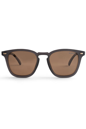 The Liive Manhattan Polar Sunglasses feature black frames with brown tinted, polarized lenses that provide UV protection. With a classic rectangular design, these sunglasses are perfect for both casual and formal occasions. The durable polycarbonate frame withstands everyday use, and the plain white backdrop accentuates the sunglasses' style.