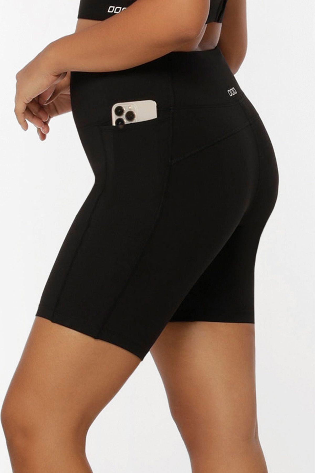 Someone models the Lorna Jane Amy Phone Pocket Tech Bike Shorts, featuring a handy side pocket for a smartphone. The image showcases the shorts’ moisture-wicking fabric from the side and back.