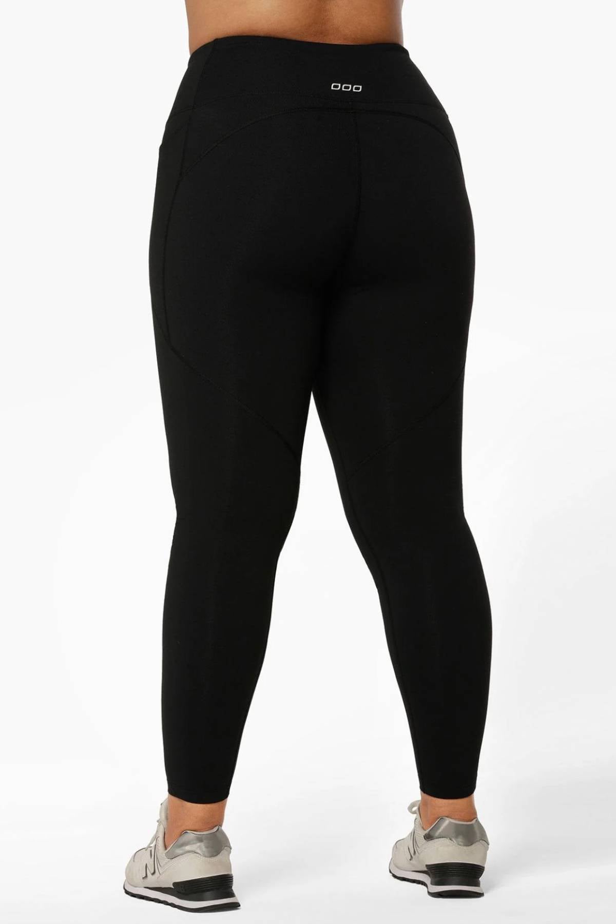 A person is shown from the back wearing Lorna Jane Amy Thermal Phone Pocket Full Length Leggings in black and light-colored athletic shoes, standing against a plain white background.