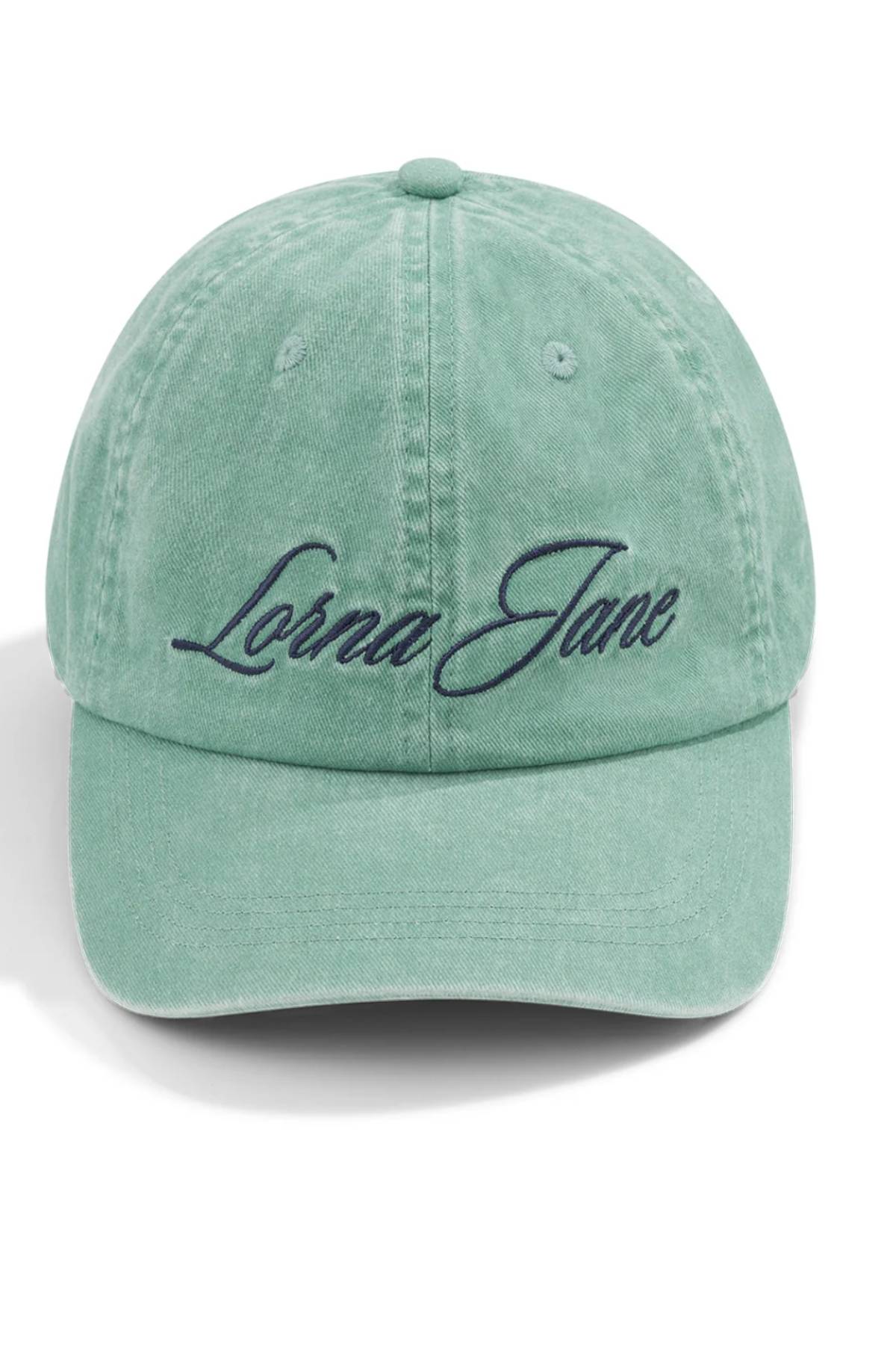 The Lorna Jane Heritage Washed Logo Cap in light green features "Lorna Jane" embroidered in dark script on the front. This vintage-style cap is shown against a plain white background.