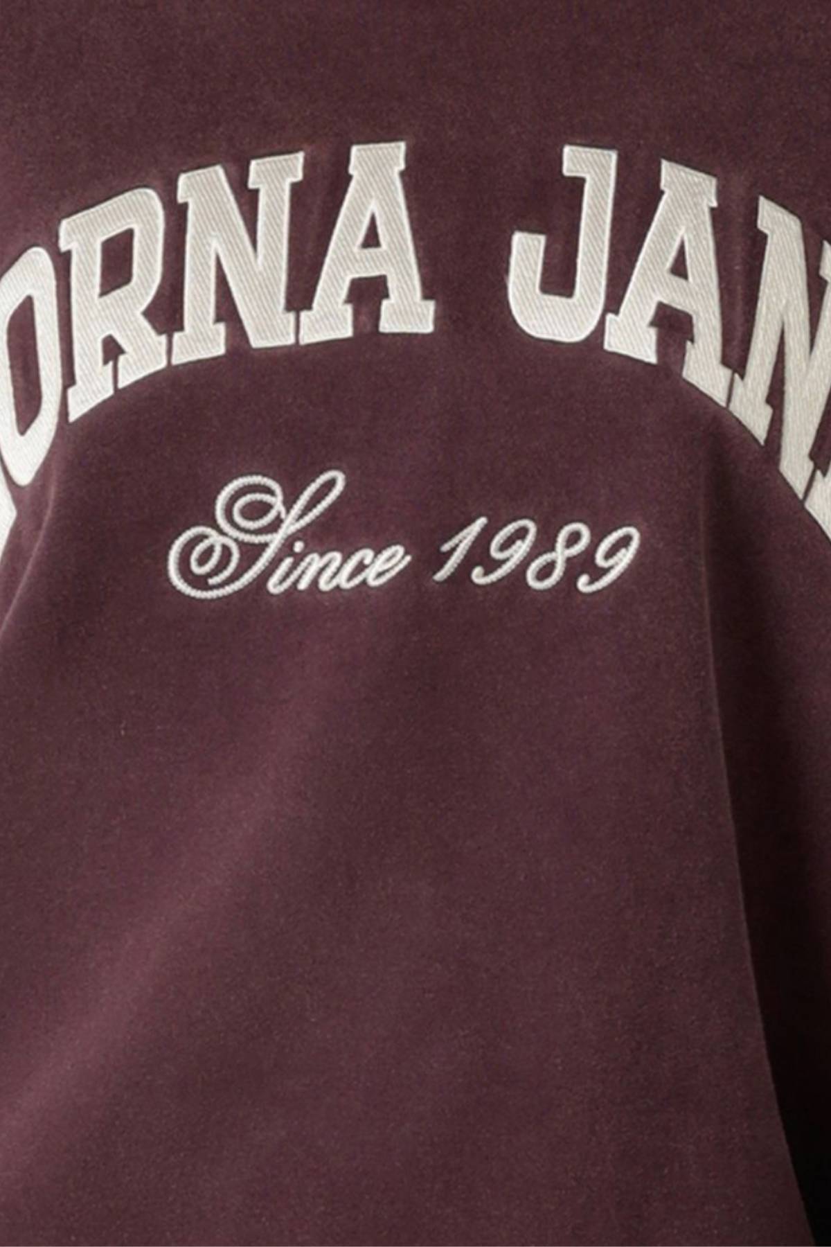 Close-up of the maroon Lorna Jane New Sport Washed Sweatshirt with large white "LORNA JANE" embroidery and "Since 1989" script, showcasing its classic look and vintage washed finish.