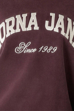 Close-up of the maroon Lorna Jane New Sport Washed Sweatshirt with large white "LORNA JANE" embroidery and "Since 1989" script, showcasing its classic look and vintage washed finish.