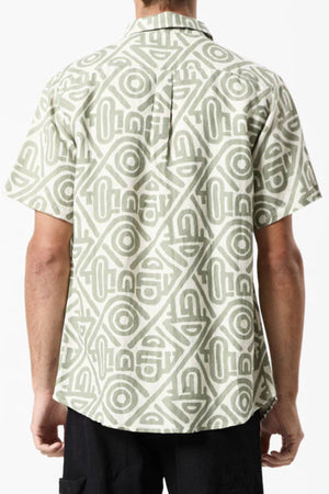 A person is seen from behind wearing a Mr Simple Earl Short Sleeve Shirt in light green and white geometric pattern. The collared, loose-fit shirt exudes a casual vibe when paired with dark pants, creating a stylishly relaxed ensemble.