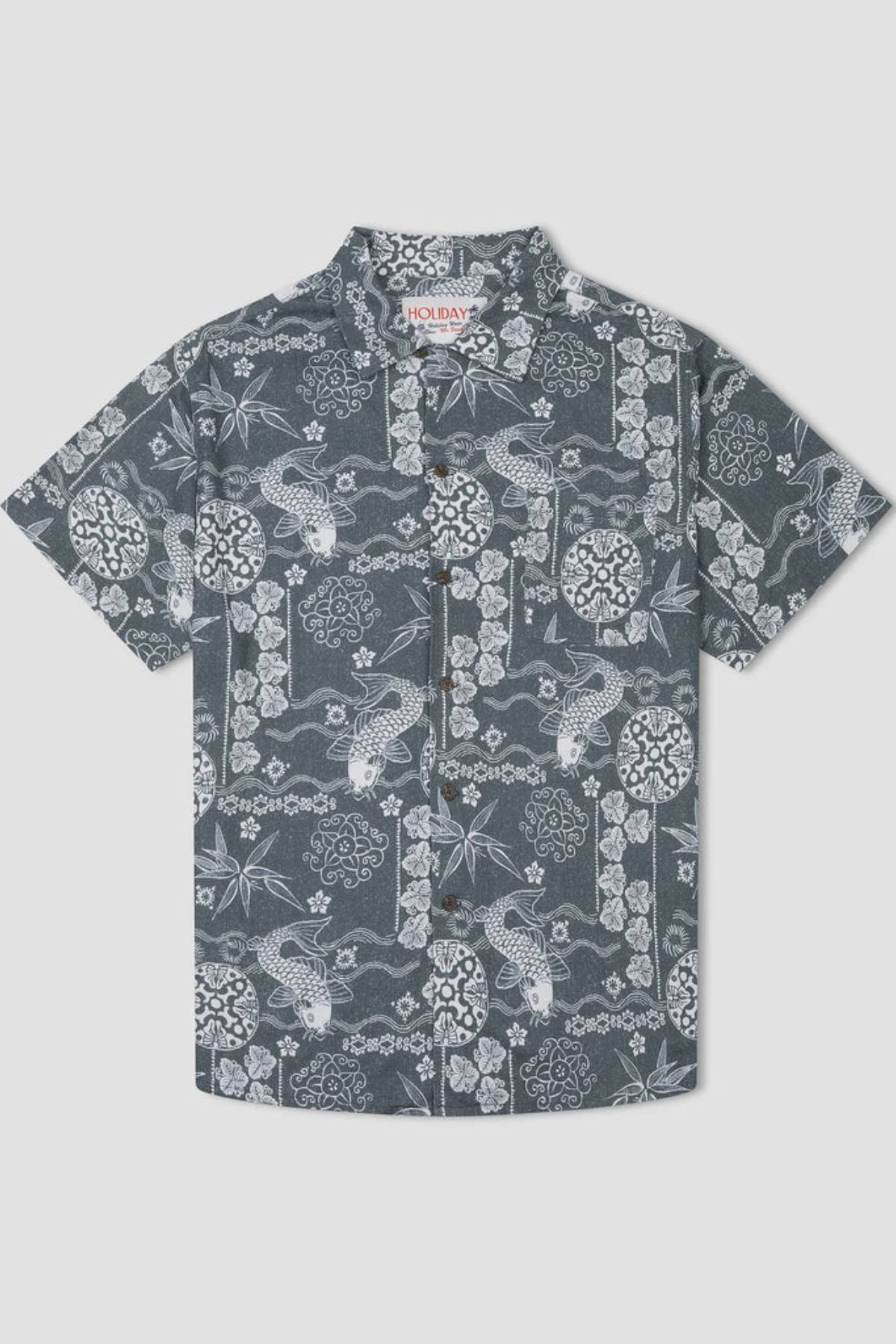 The Mr Simple Koi Bowler Short Sleeve Shirt is a short-sleeved, button-up top featuring a dark gray background adorned with an intricate white floral and fish pattern, including detailed designs of flowers, leaves, and koi fish. The collar inside the shirt sports a small label reading "Holiday.
