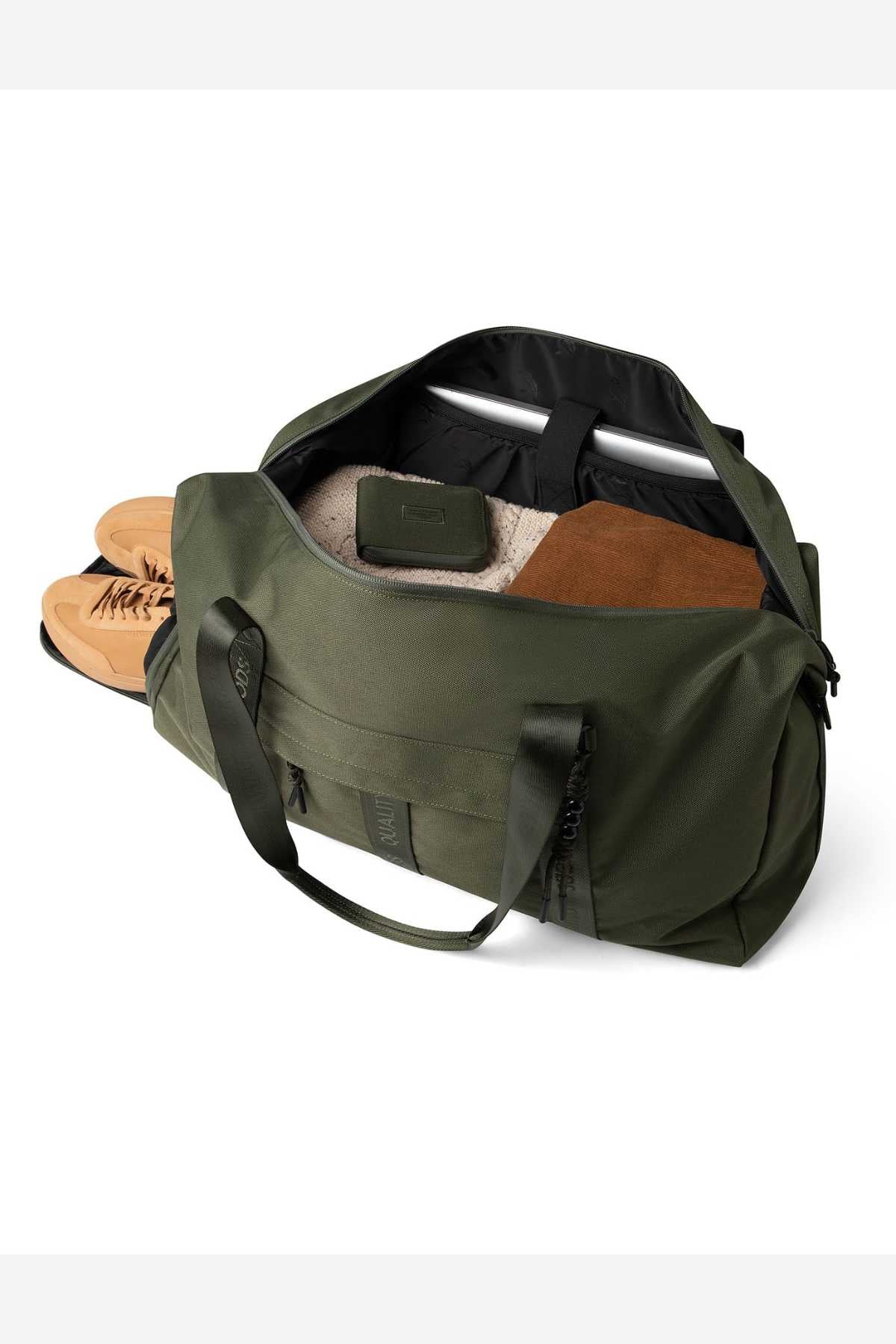 The Mr Simple Nelson Duffle, featuring sturdy handles and a shoulder strap, has an open zipper revealing a folded brown sweater, a beige item, and a small dark pouch. A pair of tan shoes is partially tucked into the side pocket.