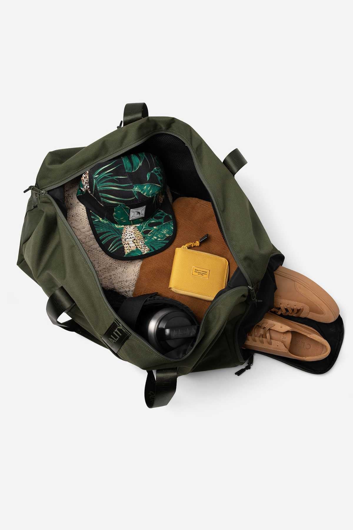 The Mr Simple Nelson Duffle is open, showcasing quality goods: a tropical-patterned cap, beige sweater, sleek black water bottle, brown pouch, yellow wallet, and tan sneakers—all set against a crisp white background.
