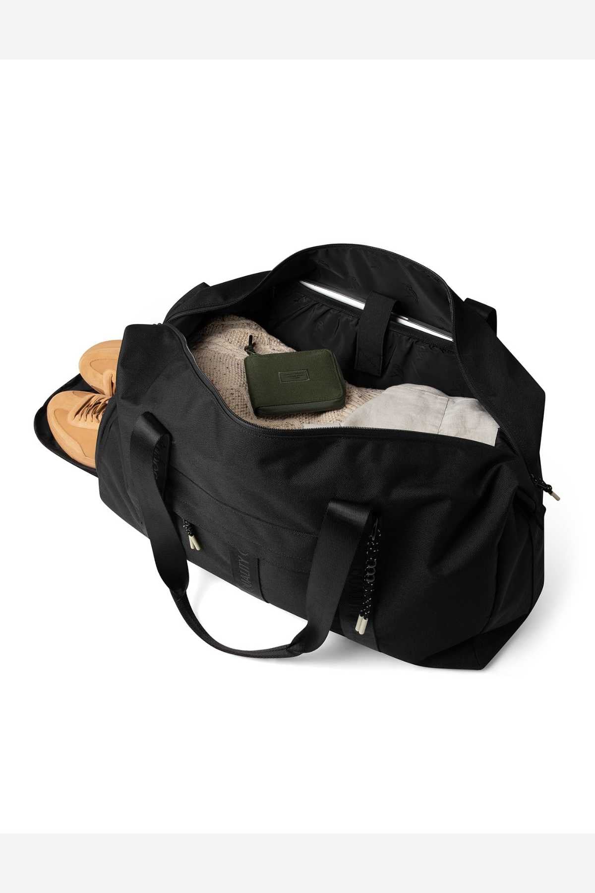 The Mr Simple Nelson Duffle, in black with a convenient trolley sleeve, sits unzipped on a white background, displaying tan shoes, a beige sweater, and a green wallet packed inside.
