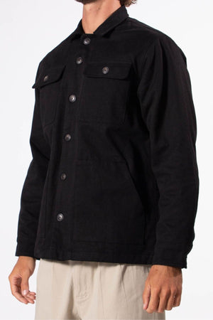 A person wears a black Mr Simple Stockyard Sherpa Jacket with chest pockets and light-colored pants, standing against a plain white background.