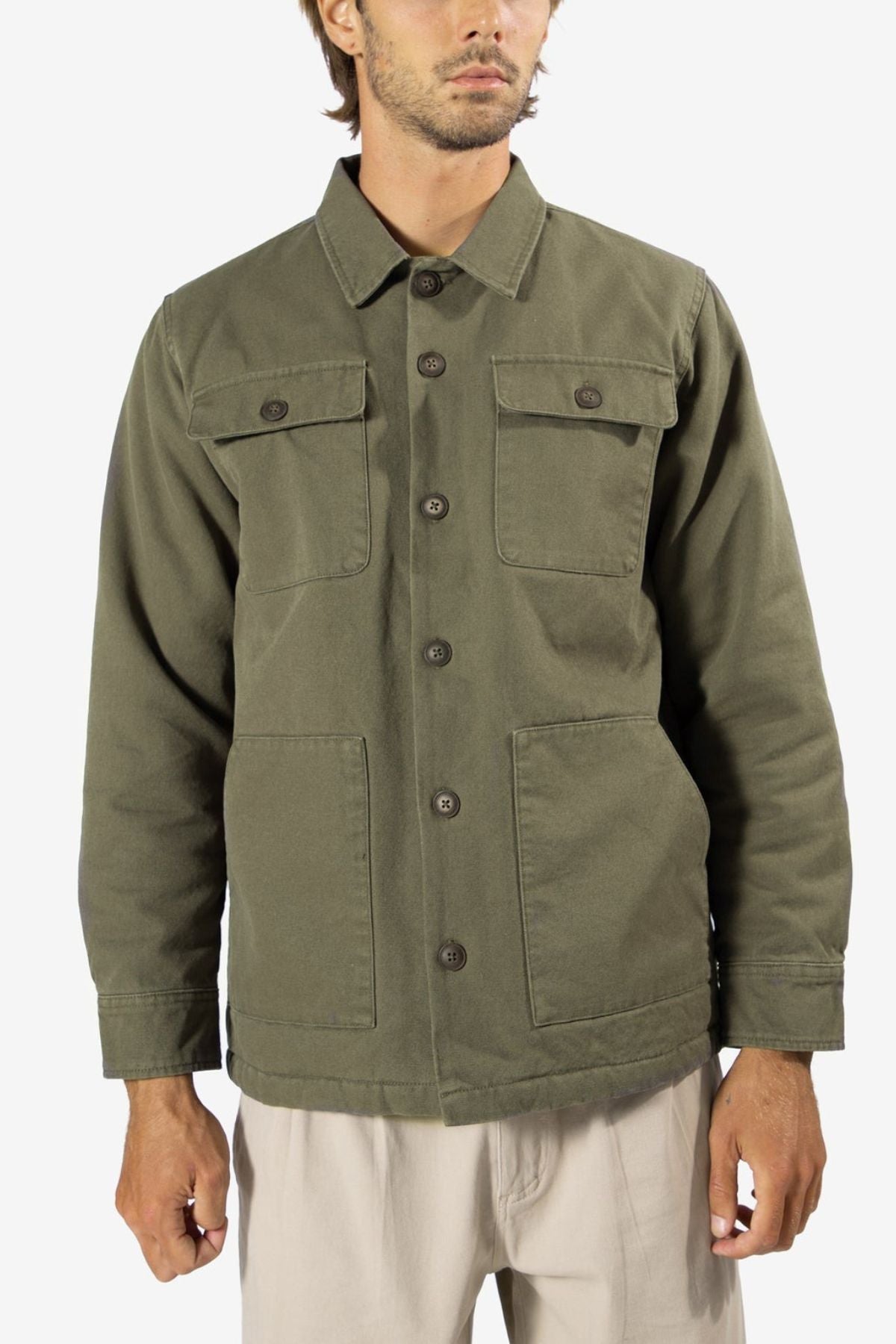 A man stands against a plain white background wearing the Mr Simple Stockyard Sherpa Jacket in olive green, featuring a regular fit, button-up front, two chest pockets, two lower front pockets, and light beige pants.