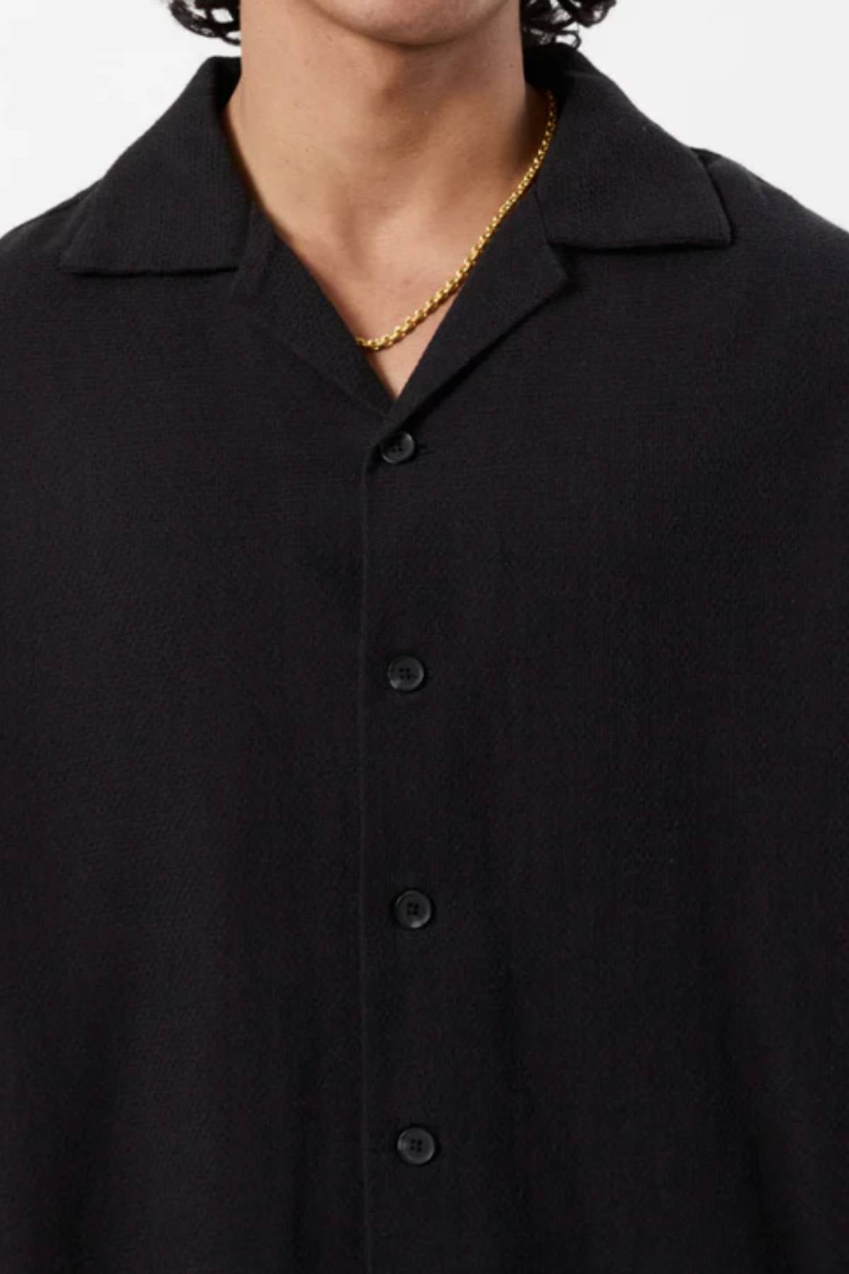 A person wears the Mr Simple Waffle Short Sleeve Shirt in black with a collar and a gold chain necklace. Only the lower face, neck, and upper chest are visible, emphasizing this versatile casual wardrobe staple.