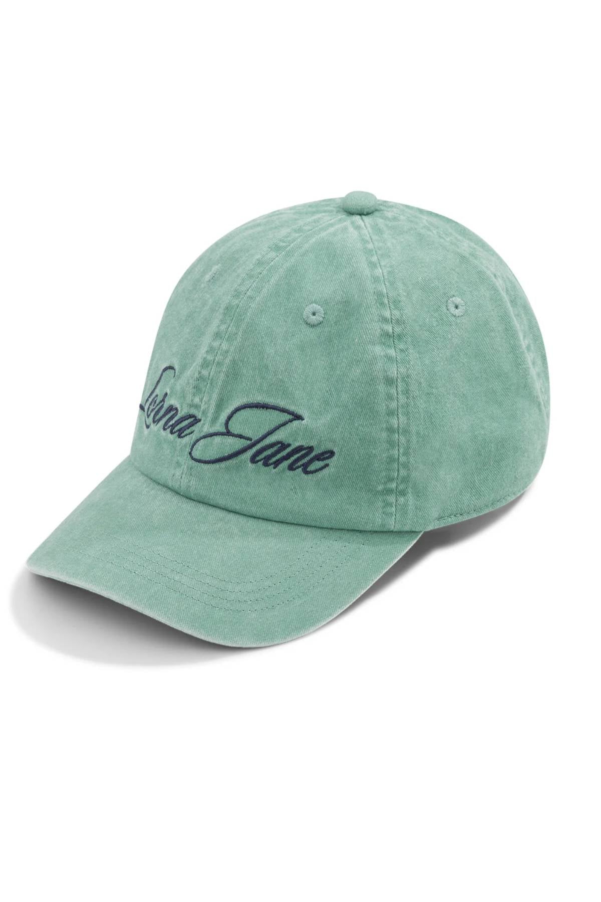 The Lorna Jane Heritage Washed Logo Cap is shown in light green with a vintage wash and "Lorna Jane" embroidered in black cursive on the front, displayed at a slight angle against a white background.