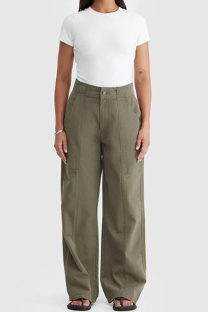 Wearing a fitted white short-sleeve tee and ORTC Avery Front Seam Pants—cotton tencel, high-waisted with large front pockets, designed in Australia—the person stands against a plain light background.