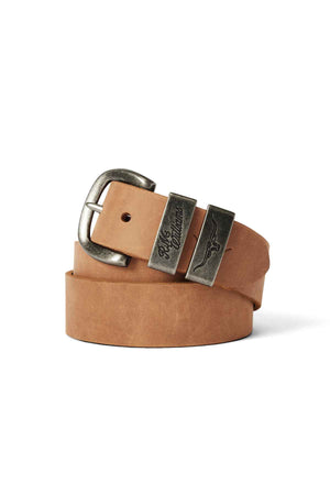 The RM Williams Drover Belt, made from light brown vegetable-tanned leather, features an antique brass buckle and two engraved metal belt loops. It comes coiled in a roll with the buckle facing forward.