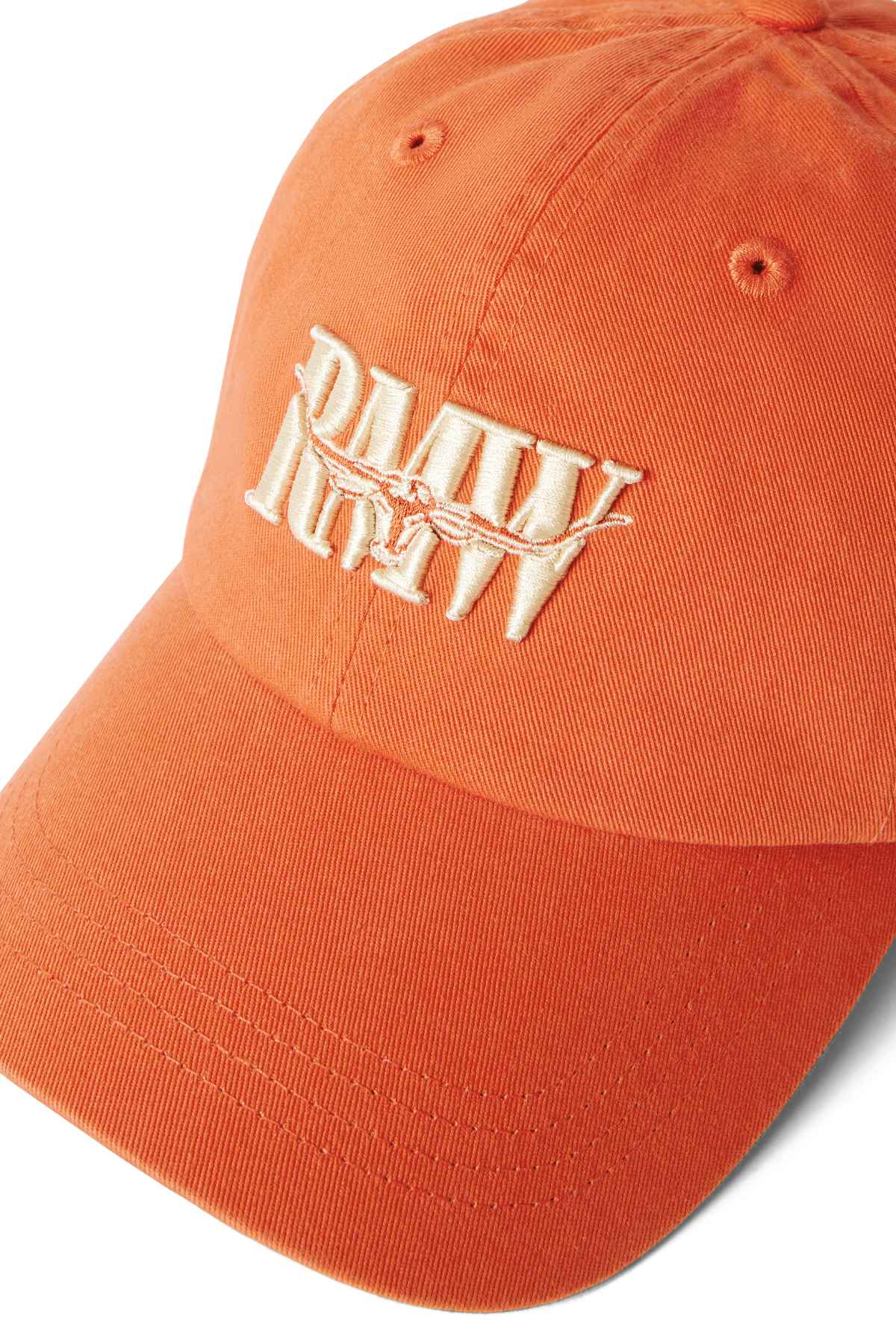 The RM Williams Steers Head Cap is a classic orange cotton twill accessory with a curved brim, featuring cream-colored embroidered lettering and a barbed wire design on the front.