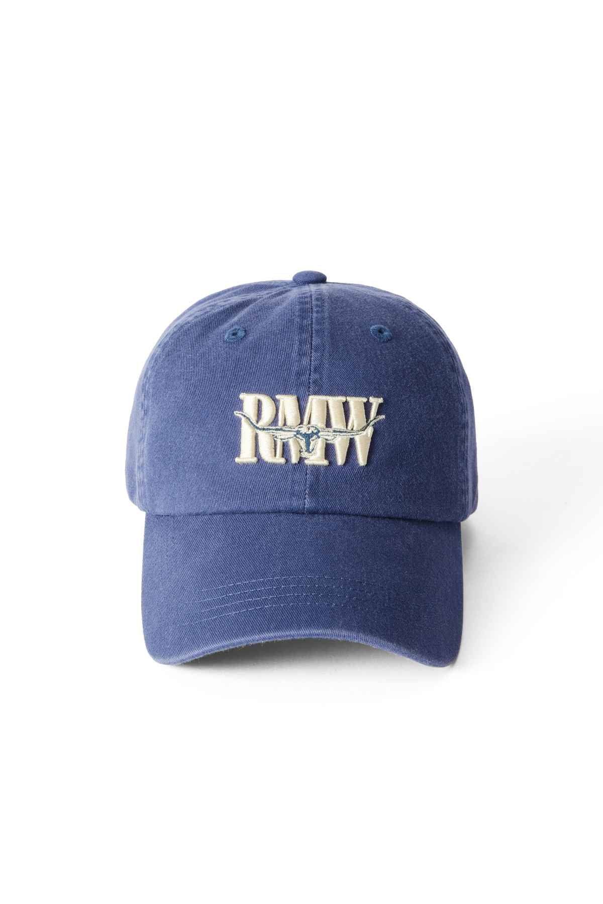 The RM Williams Steers Head Cap is a blue cotton twill baseball cap with a bold "PMW RFW" logo embroidered in white and beige on the front, archive-inspired, shown on a plain white background.