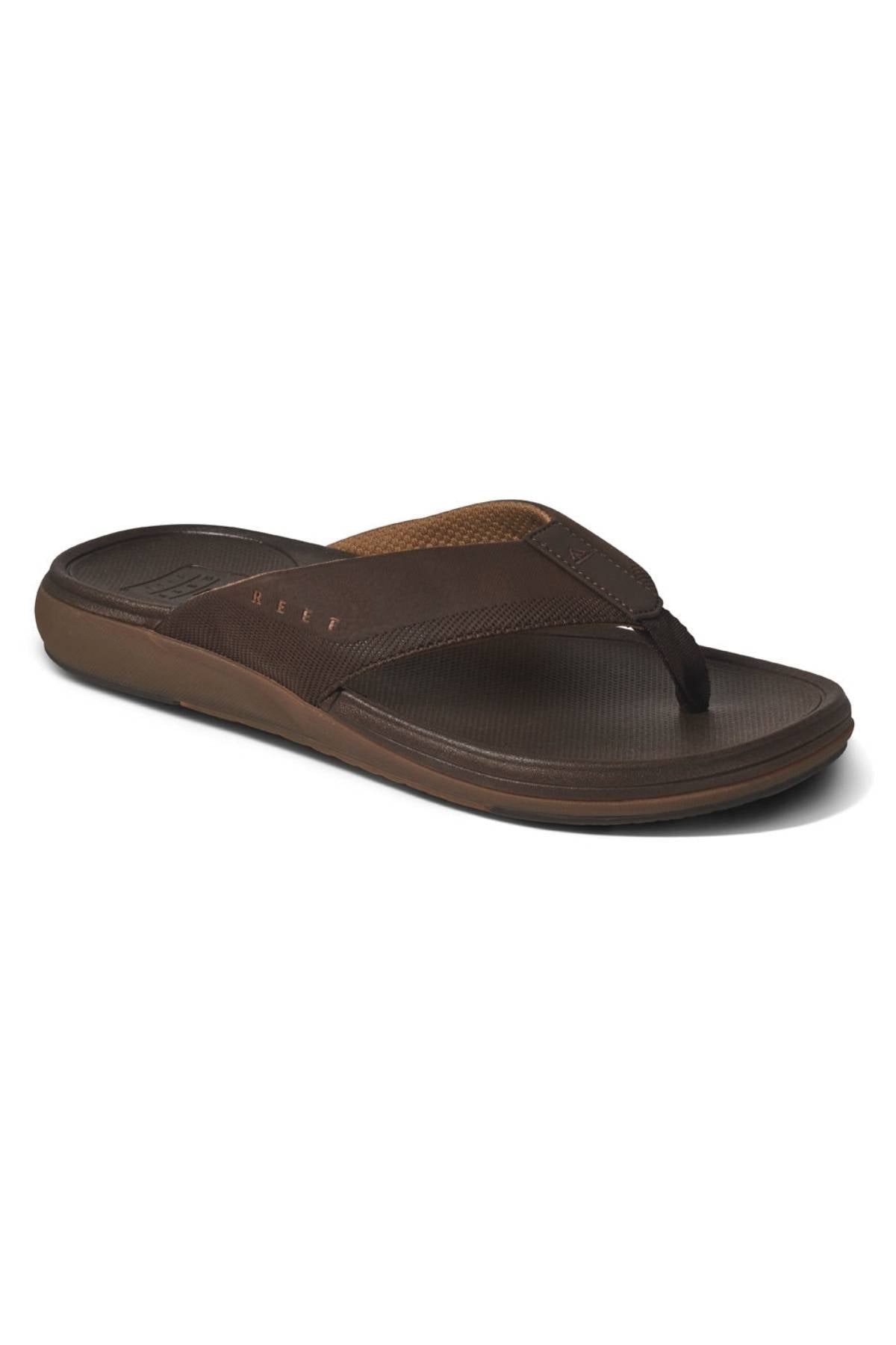 The REEF Cushion Norte sandal, shown on a white background, features a brown water-friendly design with wide fabric straps, a textured footbed, slightly raised heel, and cushioned EVA foam.