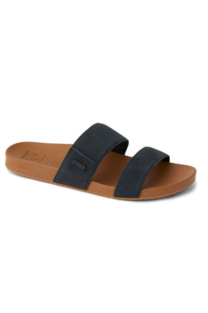 The REEF Cushion Vista Stevie is a slip-on, open-toe sandal featuring two wide black straps, a brown footbed, and a cushioned midsole for superior comfort.