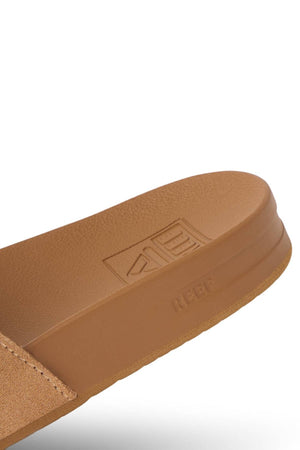 Close-up of the REEF Cushion Vista Stevie sandal in tan with suede straps, textured footbed, visible stitching, and "REEF" branding embossed on the strap and footbed. Features enhanced arch support for all-day comfort.