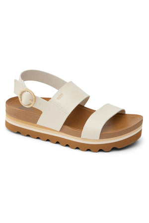 The REEF Vista Hi Buckle is a white vegan leather sandal featuring a thick tan platform sole, two wide straps, arch support, an adjustable ankle strap with a round buckle, and a wavy tread.