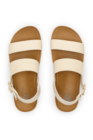 The REEF Vista Hi Buckle sandals feature tan and cream vegan leather, two wide top straps, and an ankle strap with a side buckle, shown from above on a white background.