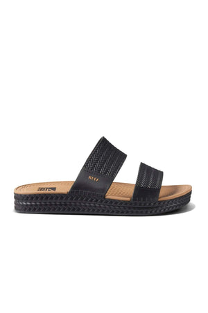 The REEF Water Vista Slide offers a stylish black sandal with two woven straps and a tan dual density EVA footbed for comfort. Its textured black sole adds a casual touch, making this waterproof sandal ideal for warm weather outfits.