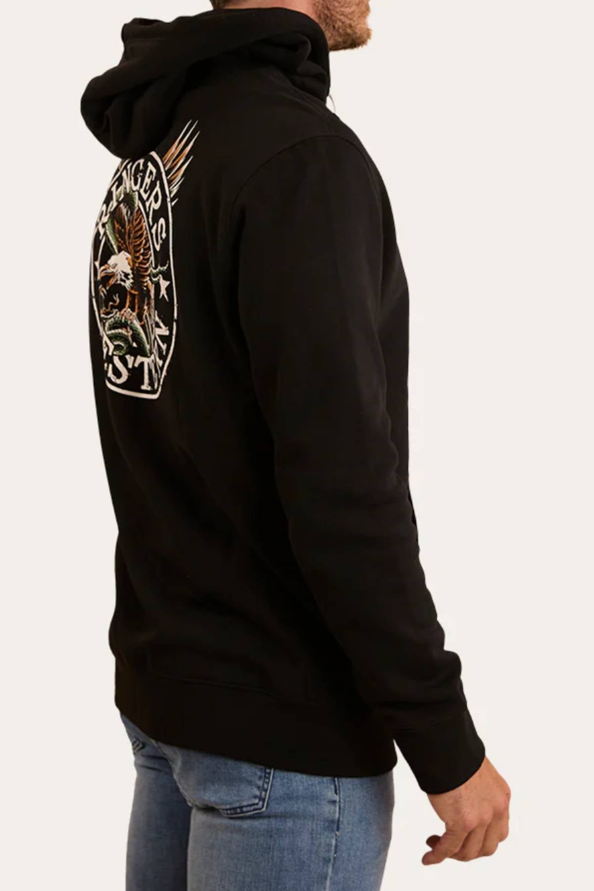 A man in the Ringers Western Eyrie Pullover Hoodie, featuring an embroidered eagle and "RANGERS" on the back, stands sideways in blue jeans, looking left. The brushed fleece fabric enhances his comfortable, casual style.