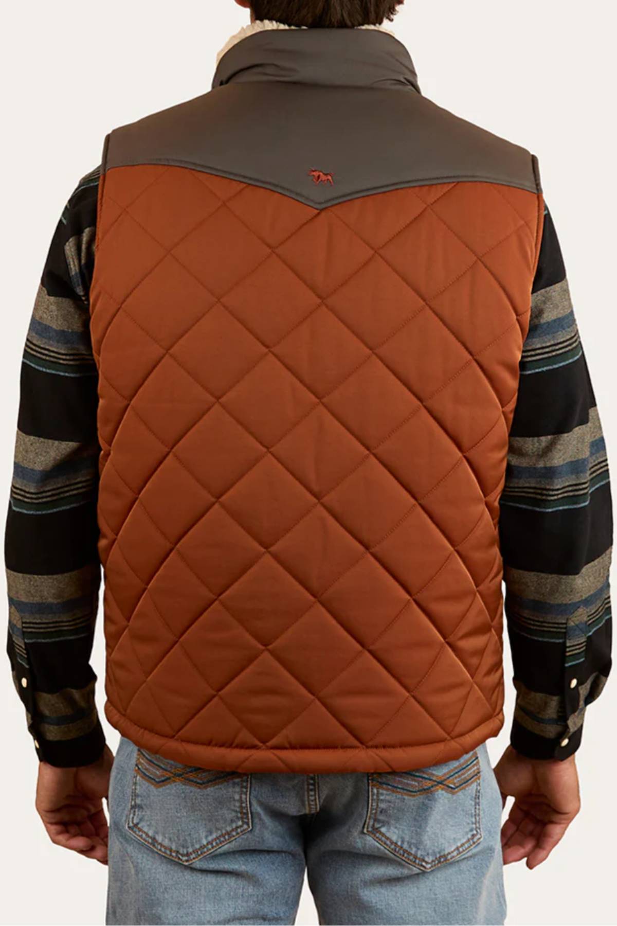 A person wearing the Ringers Western McKinlay Puffer Vest—a brown, lightweight quilted vest with a dark gray yoke—over a striped long-sleeve shirt and blue jeans, seen from the back; ideal for outdoor enthusiasts.