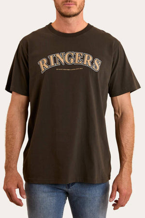 A man wears the Ringers Western Princeton Loose Fit T-Shirt in dark brown, 100% cotton, featuring "RINGERS" in large puff ink letters on the chest and small text below, paired with blue jeans.