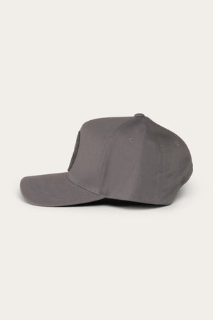 Side view of the Ringers Western Rye Baseball Cap in gray with a flat brim, six-panel construction, and stitched ventilation eyelets. The Cotton Twill cap features a circular patch logo on the front panel and is set against a plain, light background.